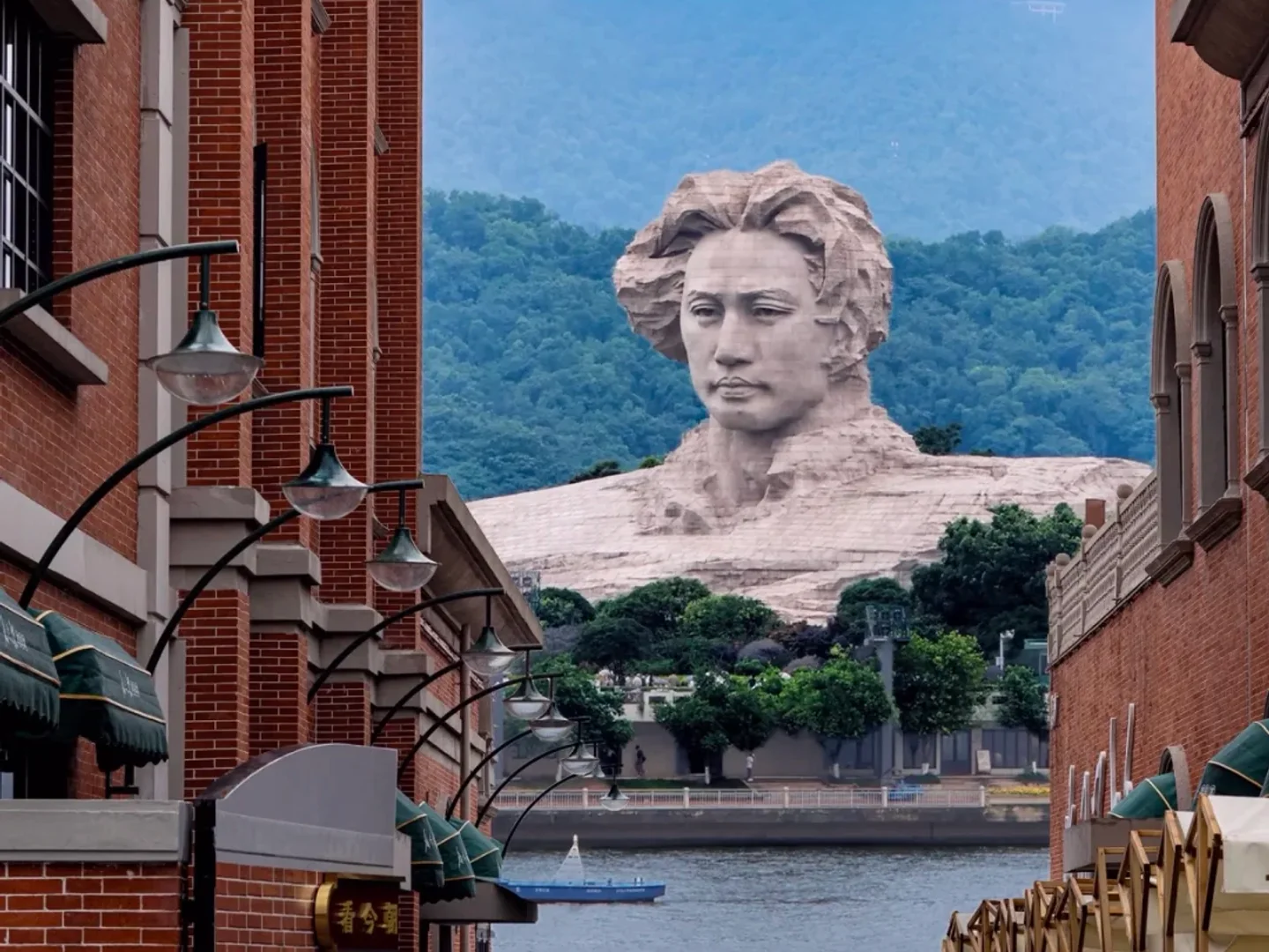 Orange Isle statue framed by red-brick buildings across the Xiang River in Changsha