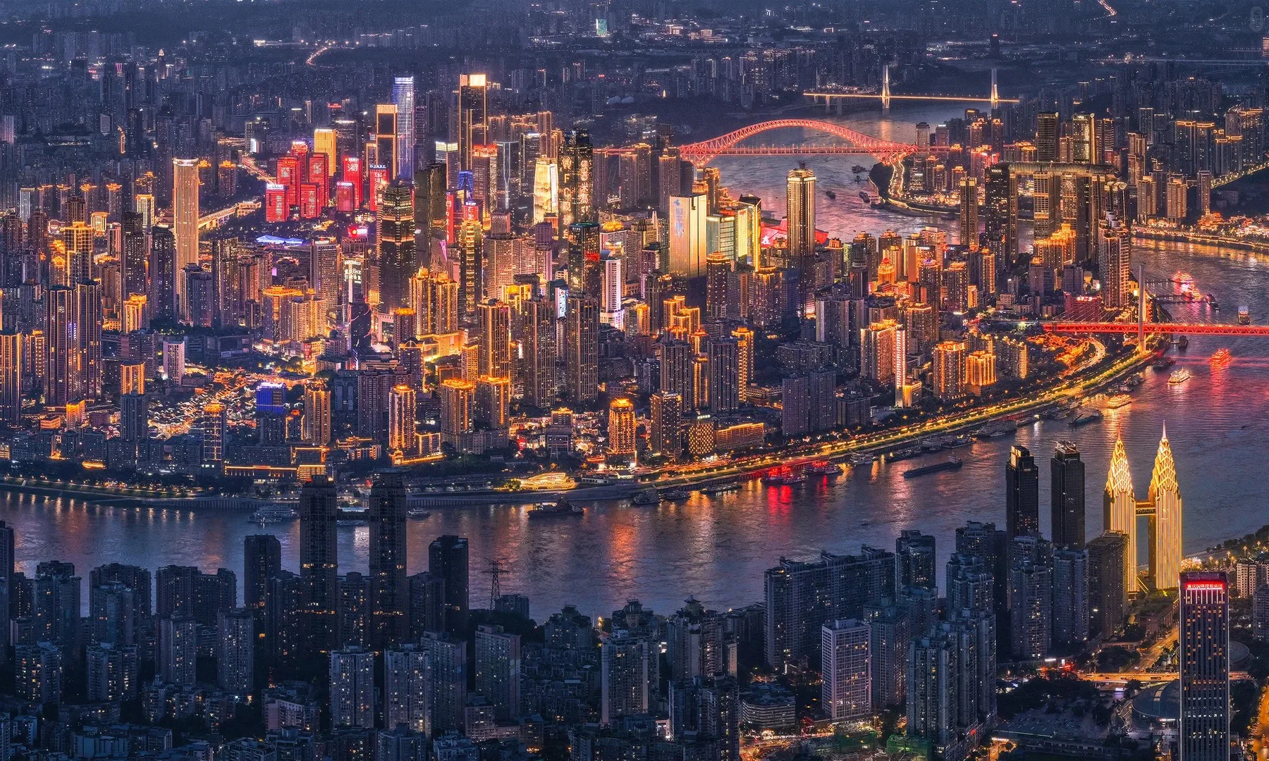 Wide aerial view of illuminated Chongqing towers between two rivers at night