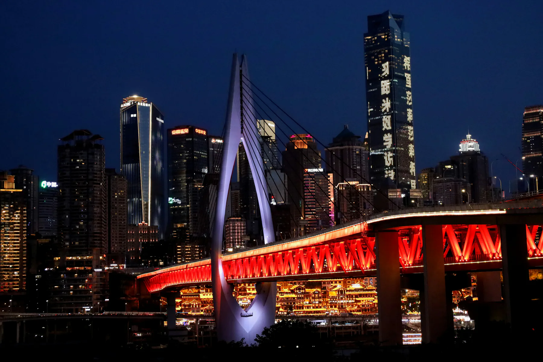 Red-lit Qiansimen Bridge in front of Chongqing towers at night