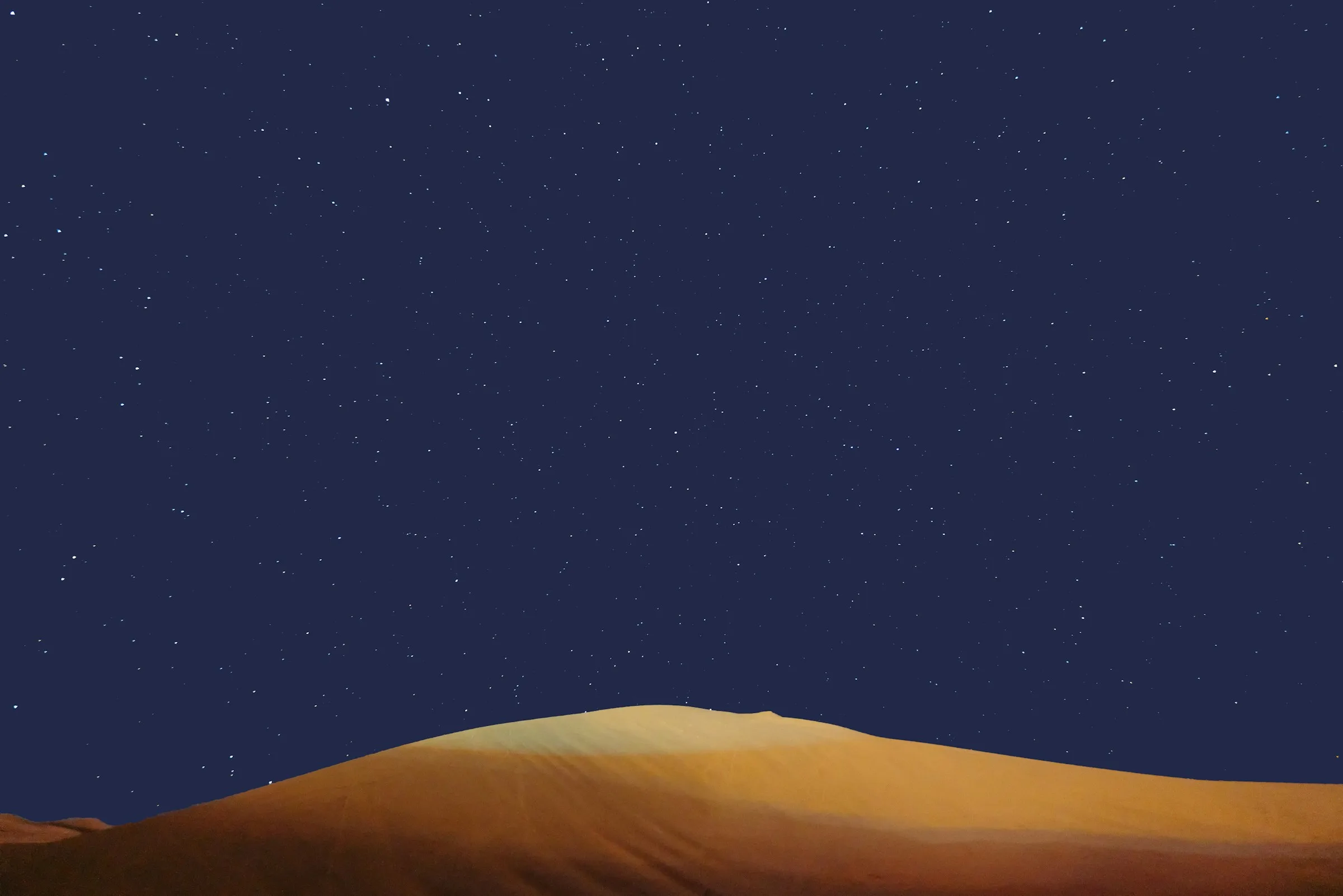 A hand holding blue fabric beneath stars above the dark outline of a sand dune near Dunhuang