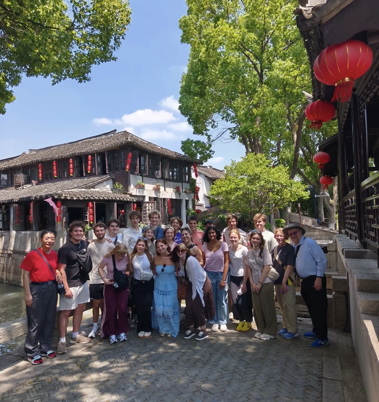 A European travel group beside traditional waterside buildings in China
