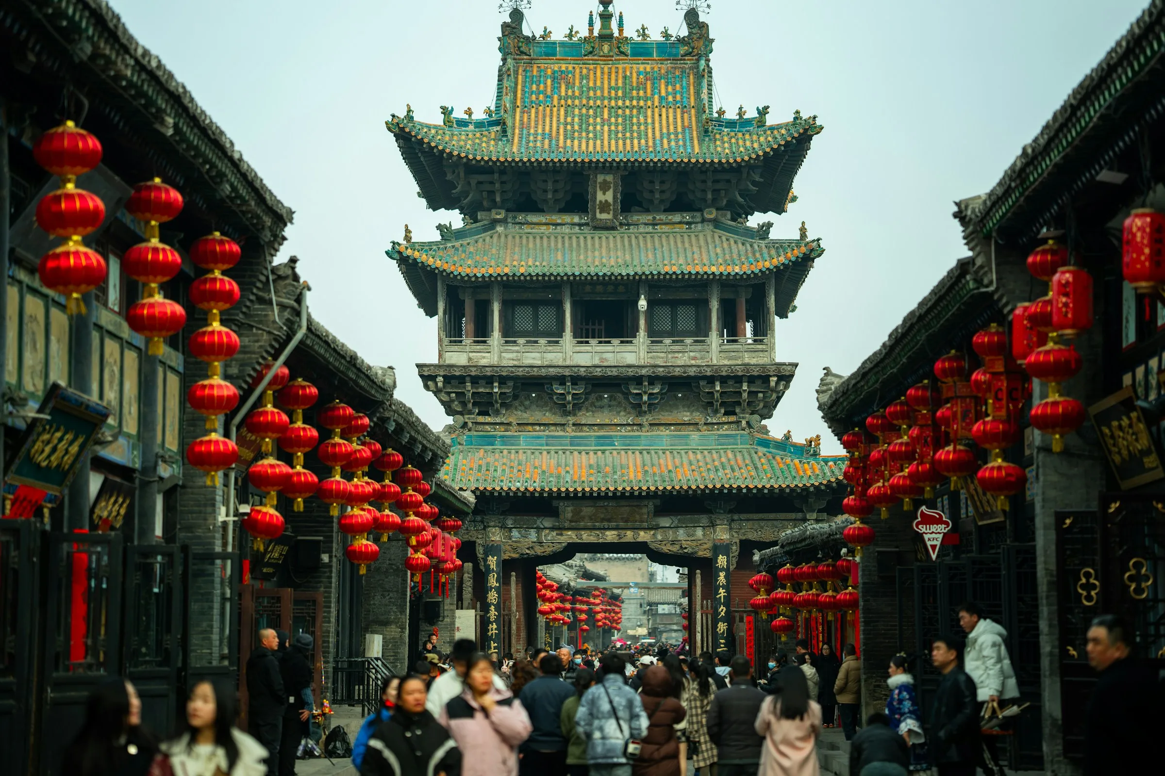 Pingyao historic market street with its traditional tower, grey-tiled shopfronts and red lanterns