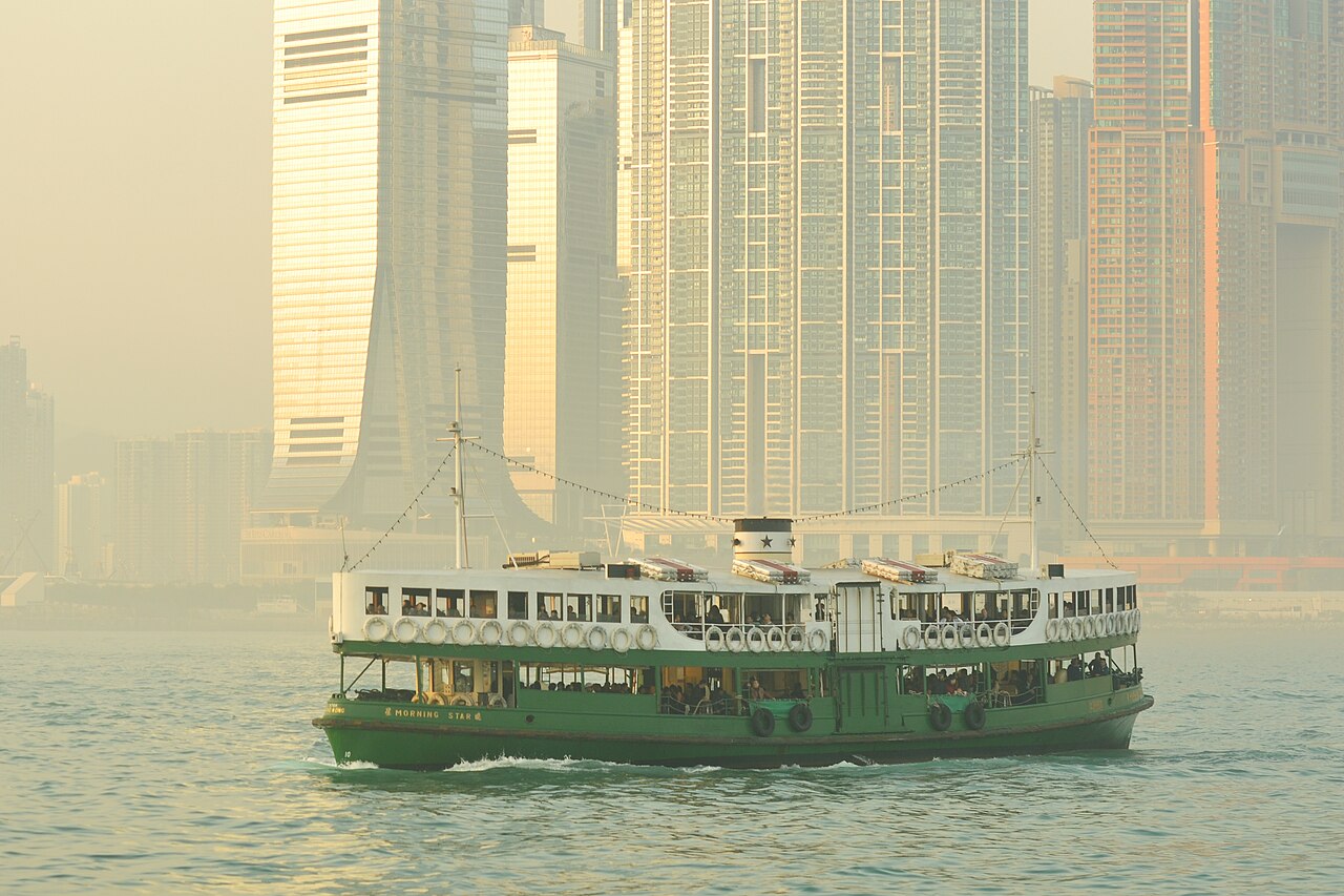 A green and white Star Ferry crossing Victoria Harbour in warm evening light