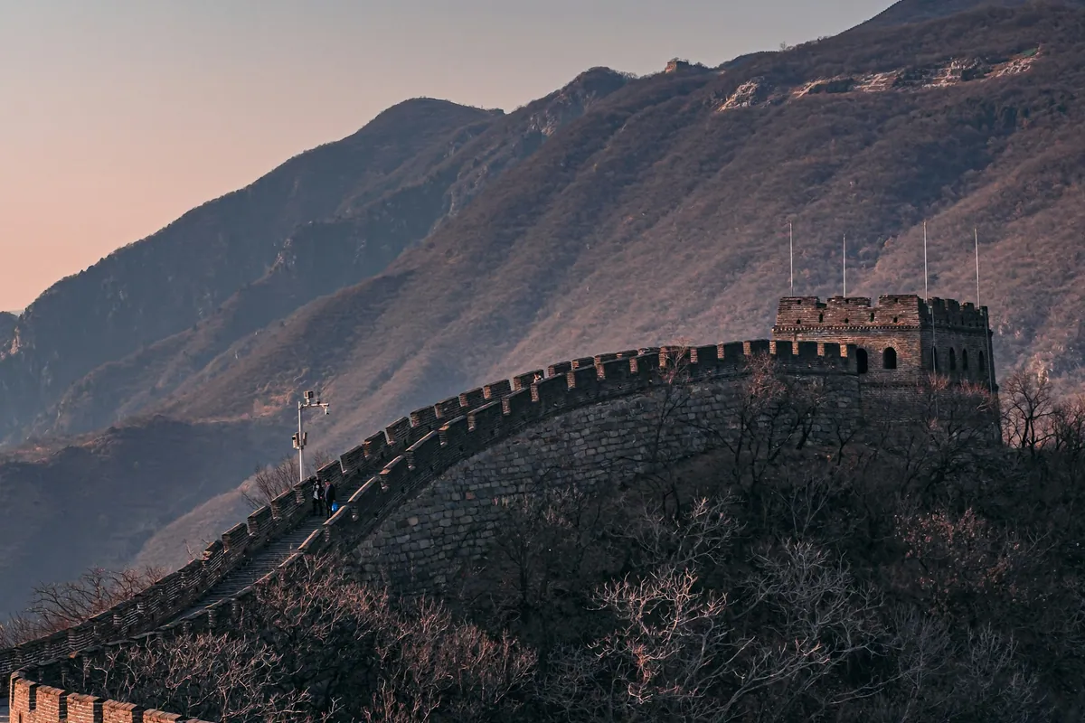 Great Wall of China at dusk with mountains behind it