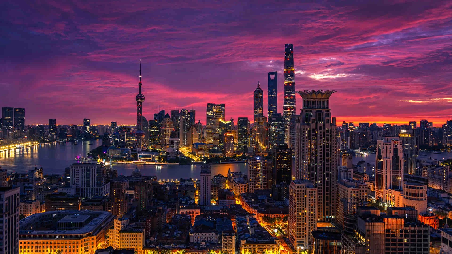 The Shanghai skyline and Huangpu River glowing after sunset