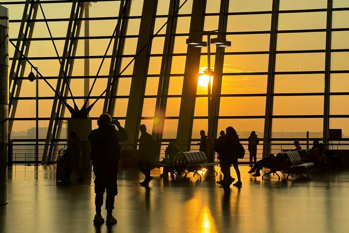 Travelers in an airport terminal at sunset
