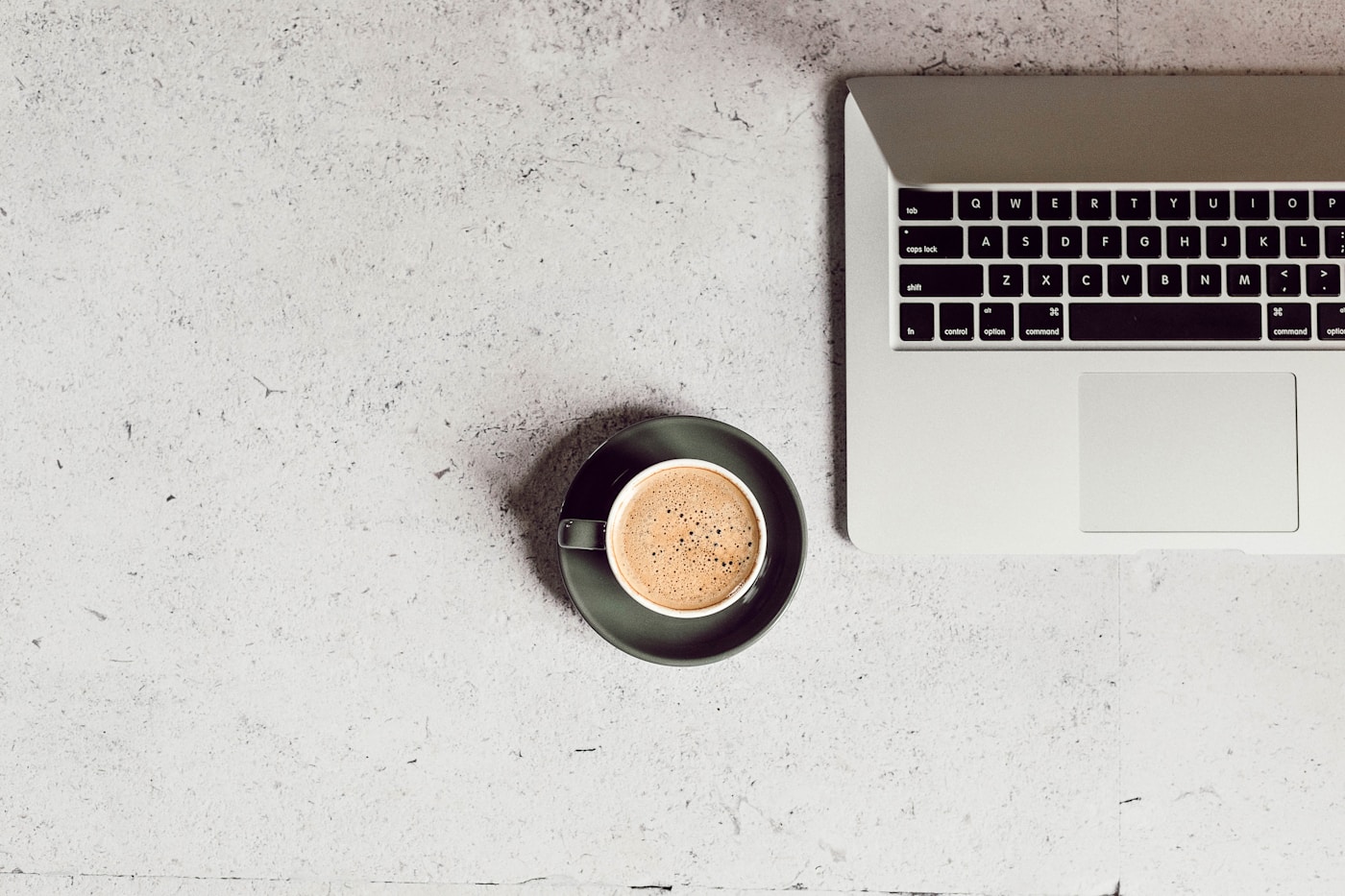 A laptop and a cup of coffee viewed from above on a café table